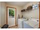 Convenient laundry room with washer, dryer, storage shelves, and a door leading to the outside at 209 Red Fern Ct, Canton, GA 30114