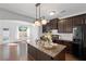 Open kitchen with island, dark cabinets, stainless appliances, and a view of the dining area at 261 Highland Village Ln, Woodstock, GA 30188