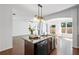 Kitchen island featuring dark cabinets, granite countertop, stainless steel dishwasher, and views into the living room at 261 Highland Village Ln, Woodstock, GA 30188