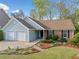 Inviting single-level home featuring a well-maintained lawn, brick facade, and two-car garage, surrounded by mature trees at 5265 Bentley Hall Dr, Alpharetta, GA 30005