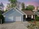 Traditional home with a two-car garage, showcasing blue vinyl siding, a brick section and a professionally landscaped front yard at 5265 Bentley Hall Dr, Alpharetta, GA 30005