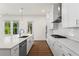 A contemporary kitchen with white cabinets, stainless steel appliances, quartz countertops, and hardwood flooring at 779 Keystone Dr, Woodstock, GA 30188