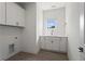 Bright laundry room with ample cabinet space, utility sink, and neutral tiling at 779 Keystone Dr, Woodstock, GA 30188