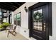 Charming front porch with chairs and a modern black door adorned with a decorative wreath at 1008 Knoxboro Ln, Woodstock, GA 30188