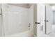 Clean bathroom featuring a white tiled bathtub and shower combination with a view of an adjoining room at 1755 Pinetree Pass Sw Ln, Lilburn, GA 30047
