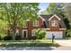 Charming two-story brick home with a well-manicured lawn, mature tree, and attached two-car garage at 1755 Pinetree Pass Sw Ln, Lilburn, GA 30047