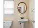 Powder room featuring a pedestal sink, framed mirror, and a window for natural light at 4095 Boles Creek Dr, Duluth, GA 30096