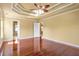 Bedroom featuring tray ceiling, windows, hardwood floors, and open doorway to the bathroom at 4095 Boles Creek Dr, Duluth, GA 30096