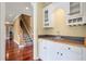 Wet bar with white cabinetry adjacent to the staircase with a carpeted runner at 4095 Boles Creek Dr, Duluth, GA 30096
