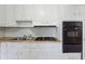 This kitchen showcases a stainless steel sink, white cabinets, and a black oven and cooktop at 8554 Taylor Rd, Riverdale, GA 30274