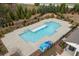 Aerial view shows a large pool with a concrete deck, dark metal fence, and evergreen trees at 228 Idylwilde Way, Canton, GA 30115