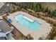 A community pool is surrounded by a concrete deck, a dark fence, trimmed shrubs and evergreen trees at 228 Idylwilde Way, Canton, GA 30115