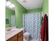 Well-lit bathroom featuring green walls, a shower with a decorative curtain and a wood vanity at 4070 Amber Leaf Dr, Roswell, GA 30076