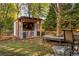 A backyard featuring a bar area, seating, and wood storage, set amongst trees and string lights at 225 Cotton Field Ct, Alpharetta, GA 30022