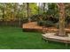 Landscaped backyard featuring a tree-surrounding platform, wooden retaining walls, and wrought iron fencing at 225 Cotton Field Ct, Alpharetta, GA 30022