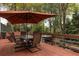 Relaxing deck featuring outdoor dining under a shade umbrella and views of the trees and lower custom bar area at 225 Cotton Field Ct, Alpharetta, GA 30022