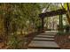 Inviting front walkway leading to the brick home, framed by lush landscaping and a rustic wooden pergola at 225 Cotton Field Ct, Alpharetta, GA 30022