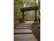 Inviting front yard featuring a wooden walkway framed by a pergola, leading to a well-maintained brick home at 225 Cotton Field Ct, Alpharetta, GA 30022