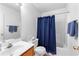 Cozy bathroom features a shower with blue curtain, toilet and sink with mirror and towel rack at 9283 Whaleys Lake Ln, Jonesboro, GA 30238