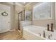 Bathroom with a garden tub, glass shower, tan tiles, wood tile floors, and a white door at 5035 Castlegate Ct, Cumming, GA 30040