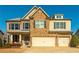 Inviting two-story home featuring brick and stone facade, complemented by a three-car garage and manicured lawn at 5390 Chestnut Dr, Cumming, GA 30040