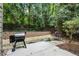 Private backyard patio area with a Traeger smoker, landscaping, and a wooded view at 1519 Dolcetto Nw Trce # 1, Kennesaw, GA 30152