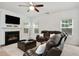 Comfortable living room with a fireplace, large windows, and plush leather seating under a modern ceiling fan at 1519 Dolcetto Nw Trce # 1, Kennesaw, GA 30152