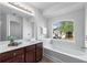 Bathroom featuring wood vanity, soaking tub with window, and recessed lighting at 2732 Pierce Brennen Ct, Lawrenceville, GA 30043