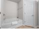 Bright bathroom featuring a soaking tub with towel, and a white paneled door at 2732 Pierce Brennen Ct, Lawrenceville, GA 30043