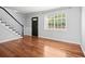 Open-concept living room with beautiful hardwood floors, stairs to the left, and a window at 6940 Roswell Rd # 24E, Sandy Springs, GA 30328