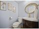 Stylish powder room with gold round mirror, vanity, wood cabinets and decorative art at 2433 Helmsdale Ne Dr, Atlanta, GA 30345