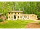 Charming yellow brick home featuring a well-manicured lawn and a lush, wooded backdrop at 2433 Helmsdale Ne Dr, Atlanta, GA 30345