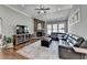 Comfortable living room featuring high ceilings, a ceiling fan, a stone fireplace, and a large leather sofa at 5320 Northview Lk, Cumming, GA 30040
