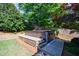 Landscaped backyard featuring a hot tub with wooden deck and steps, set against a backdrop of lush greenery and privacy fence at 2141 Abby Ne Ln, Atlanta, GA 30345