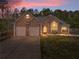 Charming brick home boasts a manicured lawn, two-car garage, and lush landscaping under a vibrant sunset sky at 3229 Summer Stream Nw Ln, Kennesaw, GA 30152
