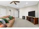 Bright living room featuring a ceiling fan, tan sofa with green pillows, and a television on a wood stand at 611 Parkside Village Nw Way, Marietta, GA 30060
