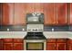 Kitchen showcases modern stainless steel stove and microwave plus stylish backsplash and cherry cabinets at 168 Ellis Dr, Conyers, GA 30012