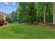 Expansive backyard featuring lush green grass and mature trees, perfect for outdoor activities and relaxation at 7020 Weybridge Dr, Cumming, GA 30040