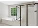 Bathroom showcases a soaking tub next to a walk-in shower, both with black trim and fixtures plus window view at 7020 Weybridge Dr, Cumming, GA 30040