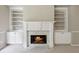 Cozy fireplace with marble surround, flanked by white built-in bookcases and cabinetry for storage and display at 7020 Weybridge Dr, Cumming, GA 30040