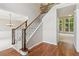 Carpeted staircase with wood and black iron railing, leading to upper level, adjacent to hardwood flooring at 7020 Weybridge Dr, Cumming, GA 30040