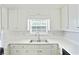 Well-lit kitchen featuring white cabinets and a stainless steel sink under a large window at 362 Mcgiboney Rd, Covington, GA 30016