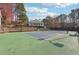 Community tennis court featuring green surface, net, lighting, tiered landscaping, and perimeter fencing at 760 Woodrow Dr, Lawrenceville, GA 30043