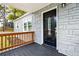Inviting front porch featuring a decorative door, stone-look exterior, a wooden railing, and well-maintained landscaping at 1623 Athens Sw Ave, Atlanta, GA 30310