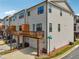 Beautiful townhouse exterior featuring a deck over the garage, white siding and manicured landscaping at 245 Fairview Cir, Roswell, GA 30076