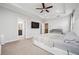 Bright bedroom featuring carpet, ceiling fan, tray ceiling, large windows, and a view of the ensuite bathroom at 245 Fairview Cir, Roswell, GA 30076