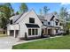 An exterior of a modern farmhouse, featuring black frame windows, a side-entry garage, and a lush green lawn at 120 Farm Gate Dr, Woodstock, GA 30188