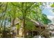 View of a two-story townhouse with a wooden deck entrance framed by mature trees at 2109 Defoors Ferry Nw Rd # D, Atlanta, GA 30318