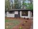 A home exterior, painted white brick, featuring stylish landscaping and contrasting black trim and dark wood privacy screen at 3572 Adkins Nw Rd, Atlanta, GA 30331