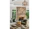 Warm living area featuring a stone fireplace, hardwood floors, large windows, and inviting seating with stylish accents at 5251 Powers Ferry Rd, Atlanta, GA 30327
